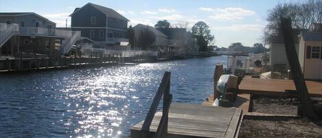 En fastighet vid vattnet med en brygga, ett hus och en liten byggnad.