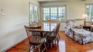 A dining area with a wooden table and chairs, a floral sofa, and large windows with a view. - North Beach Townhouse (North Beach)