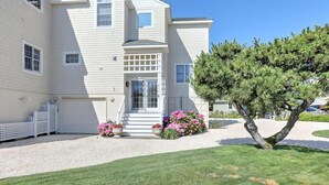 A two-story building with a white exterior, a front porch, and a small tree in the front yard. - North Beach Townhouse (North Beach)