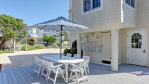 A patio with a table and chairs, a patterned umbrella, and a building with a door and window. - North Beach Townhouse (North Beach)