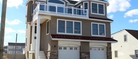 A two-story house with a balcony, a garage, and a stone foundation.