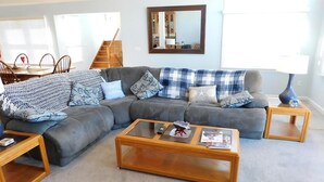 A living room with a grey sectional sofa, a wooden coffee table, and a small side table with a lamp. - pet friendly vacation rental on LBI (Brant Beach)