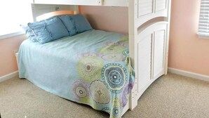 A bunk bed with a lower bunk and a top bunk, both with white headboards. There is a bedspread with a circular pattern and pillows on the lower bunk. - pet friendly vacation rental on LBI (Brant Beach)