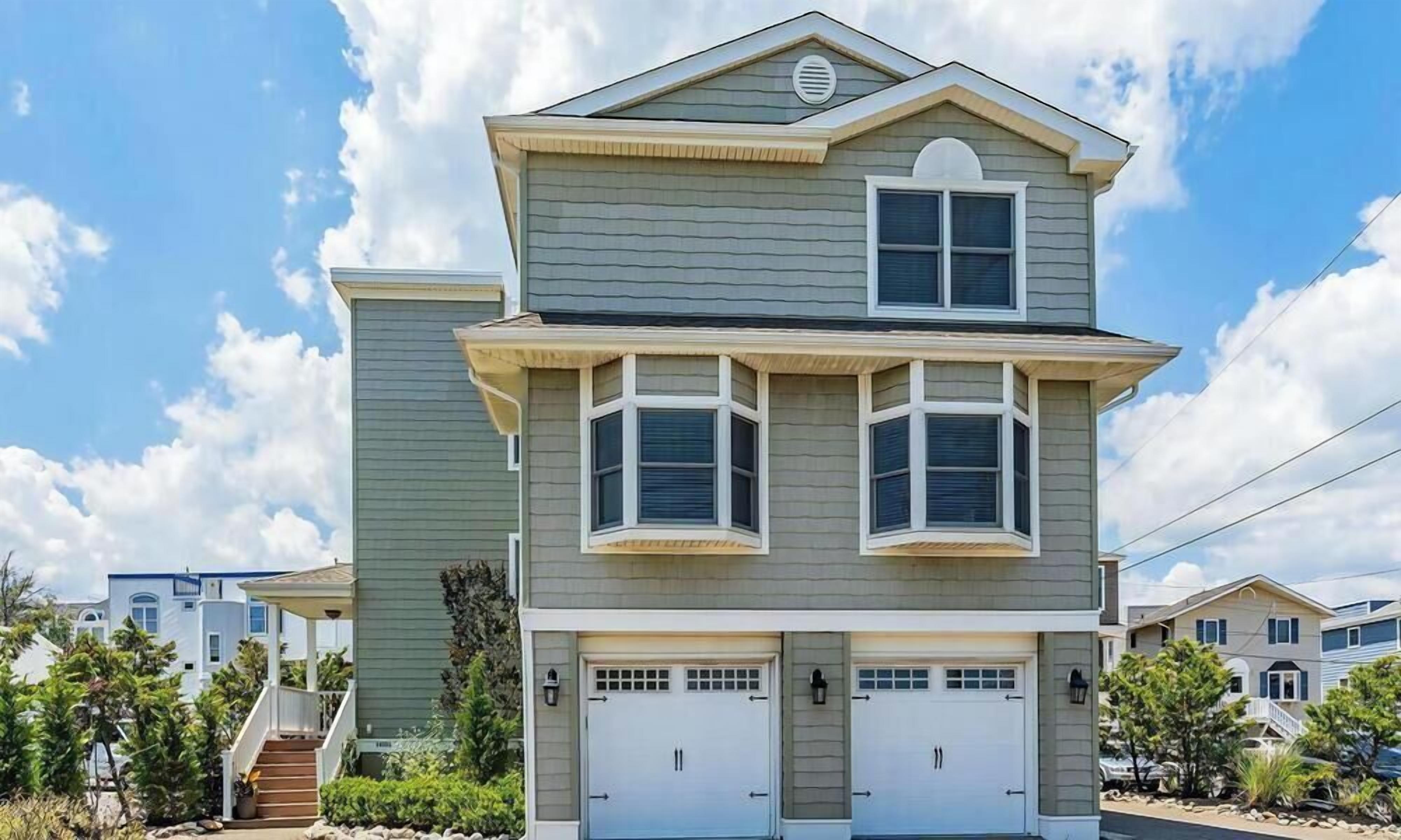 A two-story house with a garage, a covered front porch, and a staircase leading to the entrance.
