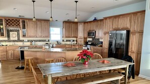 A spacious kitchen with wooden cabinets, a central island, and a dining area with a bench and chairs. - pet friendly vacation rental on LBI (Brant Beach)