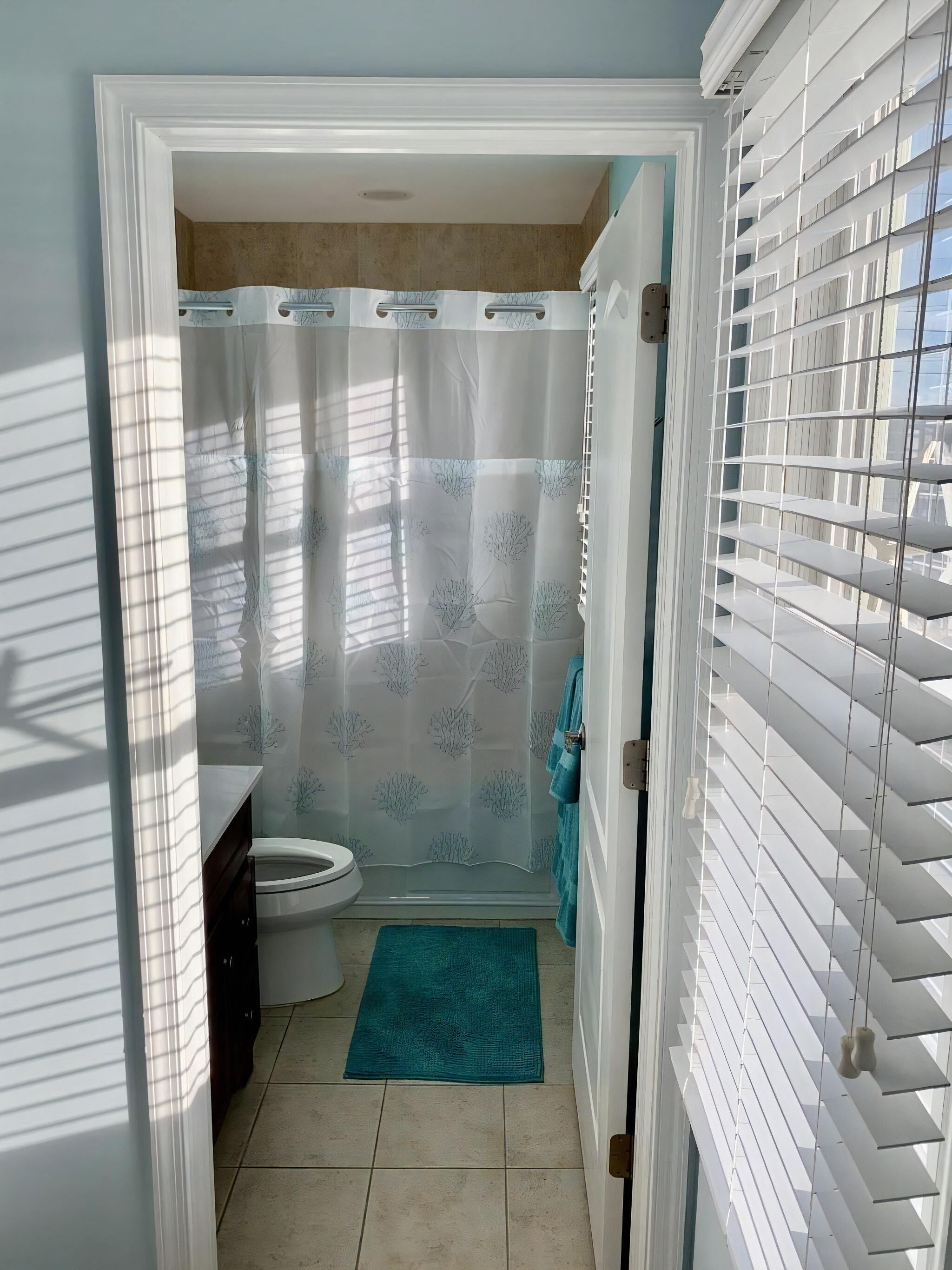 A bathroom with a toilet, shower curtain, and a towel rack.