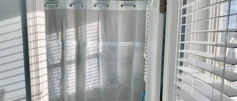 A bathroom with a toilet, shower curtain, and a towel rack.