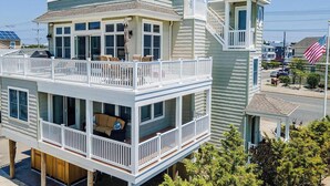 A two-story house with a balcony, a garage, and a flag. - pet friendly vacation rental on LBI (Brant Beach)