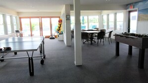 A room with a ping pong table, a foosball table, and a dining area with chairs and a table. - 2 bedroom 2 bath ocean front condo with pool in Ship Bottom first floor unit (Ship Bottom)