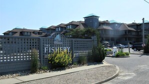 A multi-story building with a sign reading 'The Fishery.' - 2 bedroom 2 bath ocean front condo with pool in Ship Bottom first floor unit (Ship Bottom)