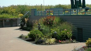 A garden area with a fountain, a wooden bench, and a paved walkway.