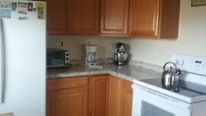 A kitchen with wooden cabinets, a refrigerator, a toaster, a kettle, and a coffee maker. - 3rd FROM THE OCEAN - SLEEPS 14! (Barnegat Light)