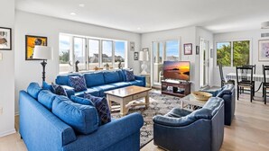 A spacious living room with a blue sofa set, a coffee table, and a flat-screen TV. - 6 BEDROOMS ON PRIVATE LANE! (Loveladies)