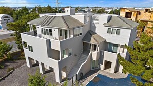 A modern multi-story house with a central staircase, multiple balconies, and a large covered outdoor area. - 6 BEDROOMS ON PRIVATE LANE! (Loveladies)