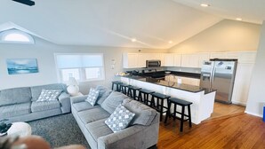 A modern kitchen with white cabinets, a stainless steel refrigerator, and a bar area.