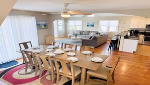 A dining area with a table set for four, a sofa, a kitchen, and a living room with a view.