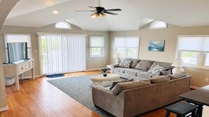 A living room with a sofa, a coffee table, a TV, and a ceiling fan.