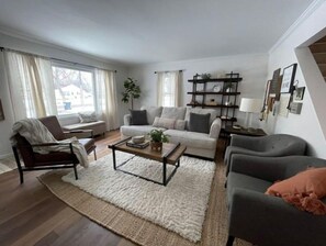 Ein modernes Wohnzimmer mit einer Couch, Sesseln, einem Couchtisch und einem Bücherregal.