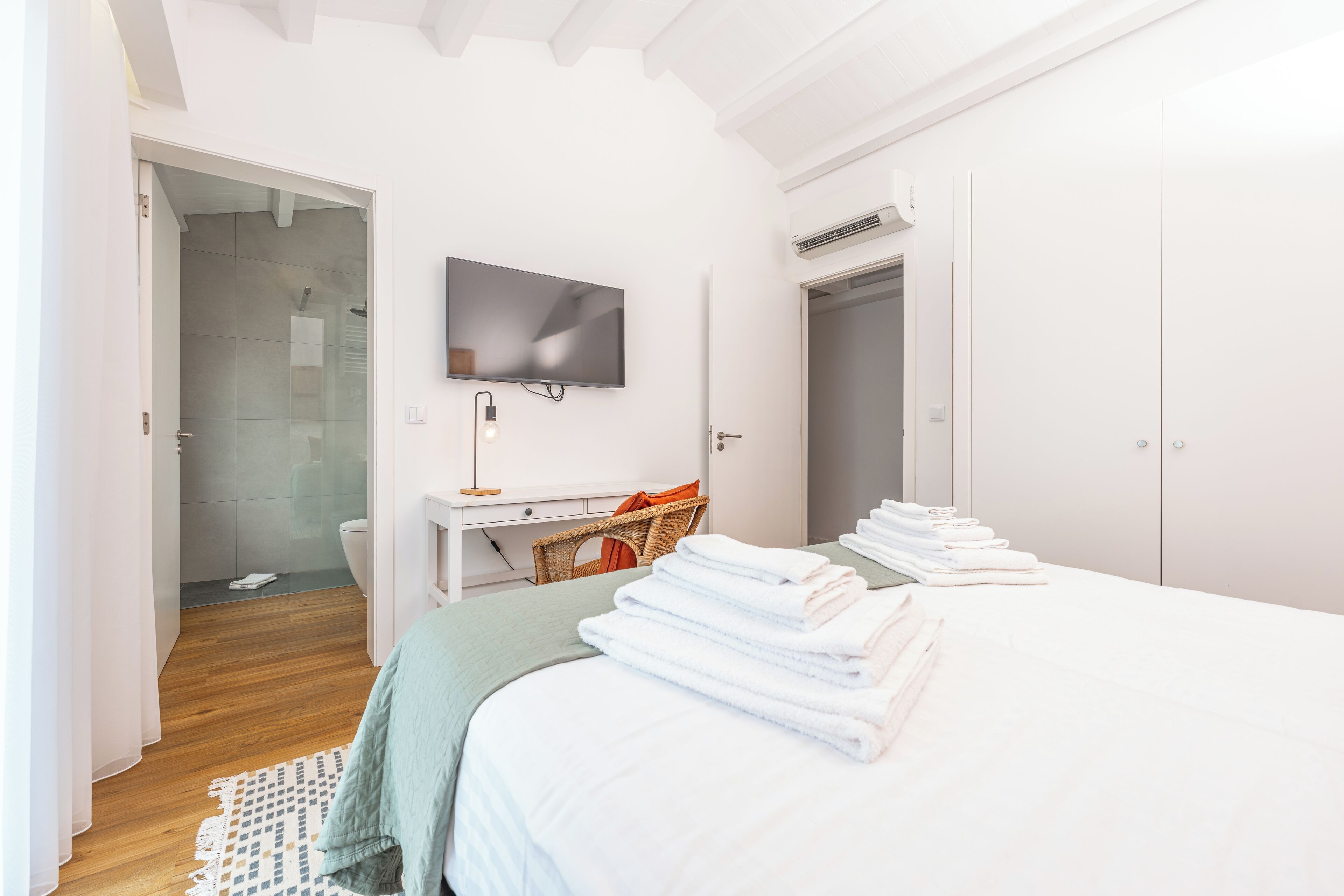 Una habitación de hotel con cama, televisión, escritorio y zona de ducha.