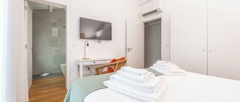 Una habitación de hotel con cama, televisión, escritorio y zona de ducha.