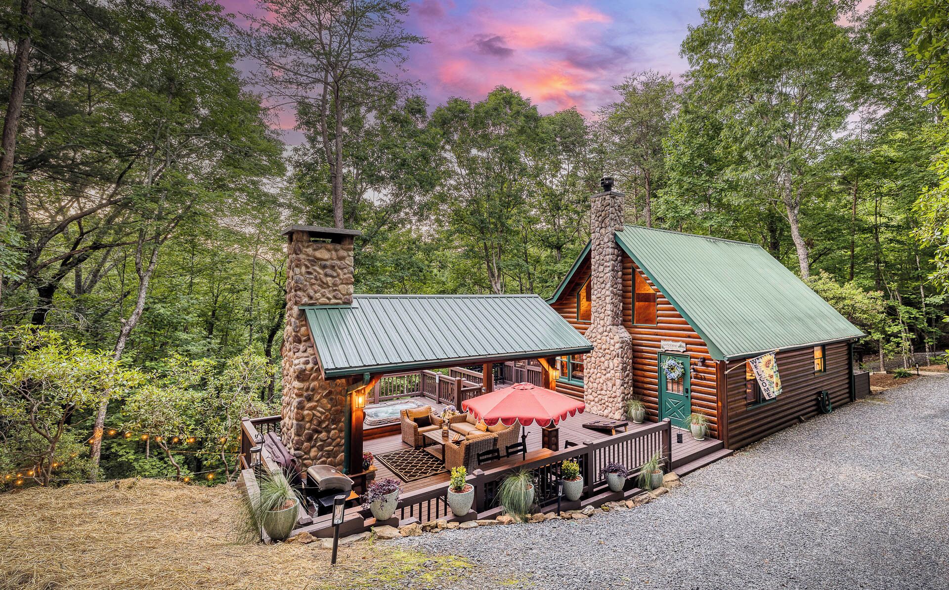 Un chalet rustique avec une cheminée en pierre, une terrasse couverte et une pancarte accueillante.