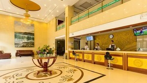 A hotel lobby with a reception desk, a large chandelier, a painting on the wall, and a decorative floor pattern. - Greentree Inn Zhengzhou Chengnan Road Bojue Hotel (Zhengzhou)