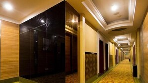 A hotel corridor with a carpeted floor, wooden and dark wall panels, and a long hallway with doors on one side. - Greentree Inn Zhengzhou Chengnan Road Bojue Hotel (Zhengzhou)
