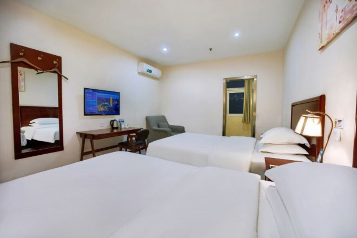 Une chambre d’hôtel avec deux lits, un bureau, une chaise, une télévision et une porte.