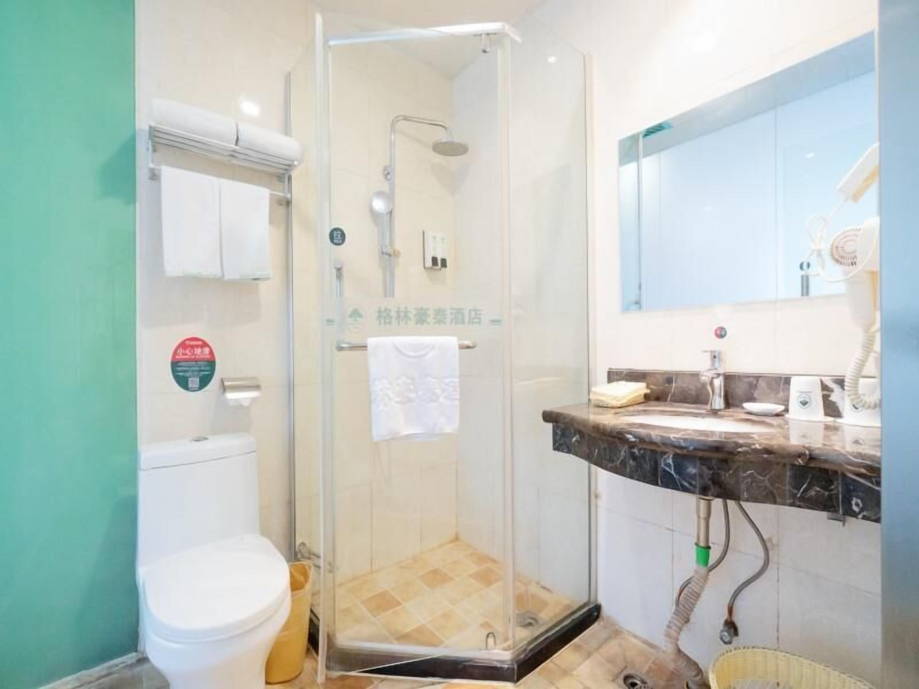Ein Badezimmer mit Duschkabine, Toilette und Waschbecken mit Spiegel.