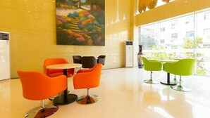 A modern lobby with orange and green chairs, a large painting, and large windows. - Greentree Inn Zhengzhou Chengnan Road Bojue Hotel (Zhengzhou)