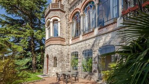 Edifício de pedra com janelas em arco e um pátio com mesa e cadeiras.