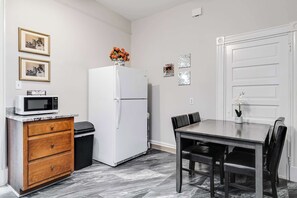 A compact kitchen with a refrigerator, microwave, and wooden cabinet.