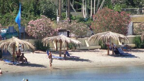 A beach with thatched umbrellas, sun loungers, and a clear view of the sea.