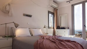Une chambre à coucher avec un lit, des lampes de chevet, une commode, un miroir et une vue sur la mer.