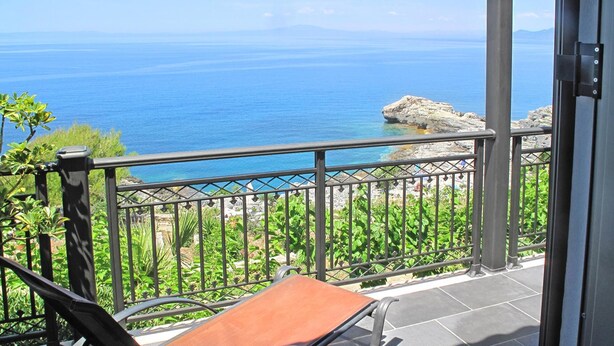 A balcony with a view of the sea and rocky coastline.