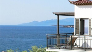 A balcony with a view of the sea and mountains.
