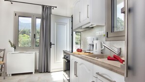 A modern kitchen with white cabinets, a Bosch coffee maker, and a view of greenery outside.
