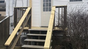 Une maison blanche avec un escalier en bois menant à la porte d’entrée.