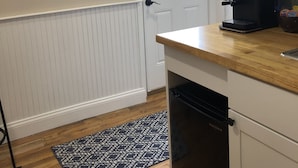 Une cuisine équipée d’une machine à café, une porte avec une fenêtre et, au mur, un cadre contenant le mot « WANDERLUST ».