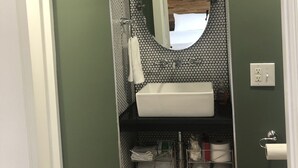 Une salle de bain avec un lavabo blanc, un miroir rond et un porte-serviettes.