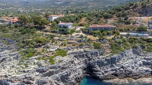 A coastal town with rocky cliffs, a clear blue sea, and residential buildings with red-tiled roofs. - Two Bedroom Apartment No 3 (West Mani)