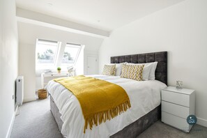 A modern bedroom with a large bed, a bedside table, and a window with a view.