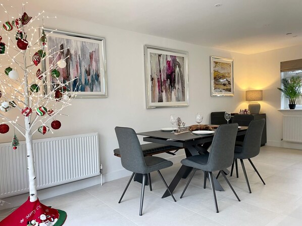 A modern dining area with a white radiator, a dining table with chairs, and Christmas decorations.
