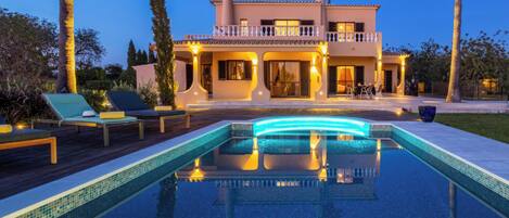 Une maison à deux étages avec une piscine en premier plan.