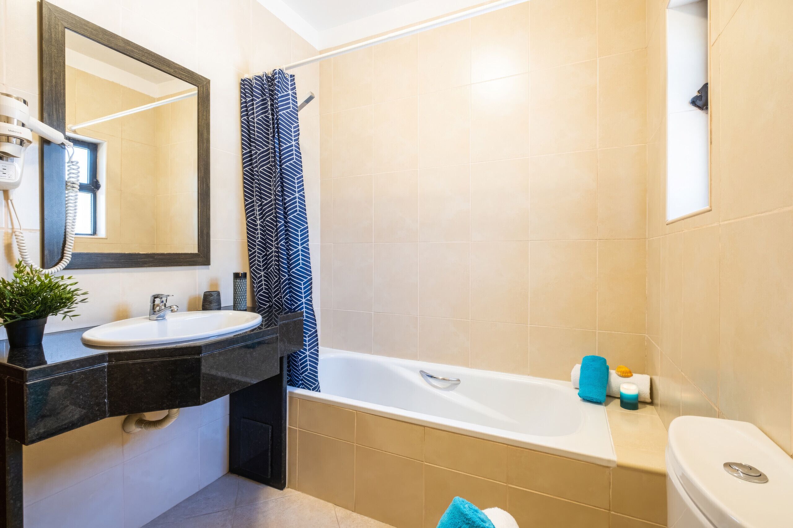 Un baño con lavamanos, espejo, cortina de ducha, bañera y retrete.