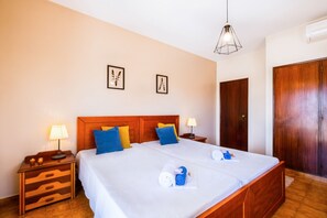 A double bed with a wooden headboard, two bedside tables with lamps, a wardrobe, and two framed butterfly pictures on the wall. - Villa with private pool and BBQ in Galé (Albufeira)