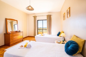 A hotel room with two beds, a wooden dresser, a mirror, a window with curtains, and a balcony view. - Villa with private pool and BBQ in Galé (Albufeira)