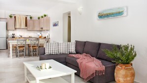 Una sala de estar moderna con un sofá gris, una mesa de centro blanca y una planta grande en maceta.