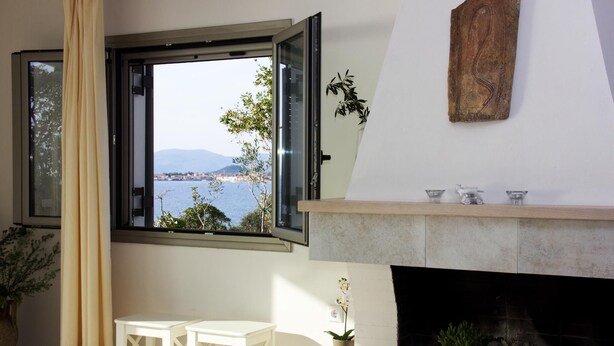 Una habitación con vistas al mar, chimenea y ventana con cortinas.