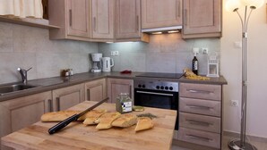 Una cocina moderna con armarios de madera, una estufa a gas, una cafetera y una tabla de cortar con pan.